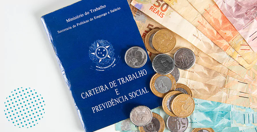 imagem de uma carteira de trabalho ao lado de moedas e notas de dinheiro