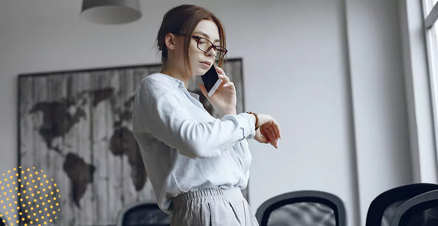imagem de uma mulher falando ao celular e olhando para seu relógio de pulso