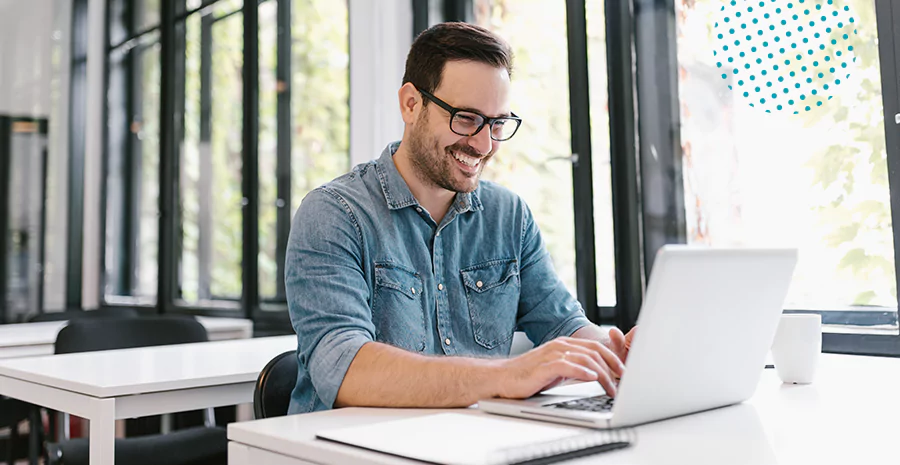 imagem de um homem sentado sorrindo digitando em um computador