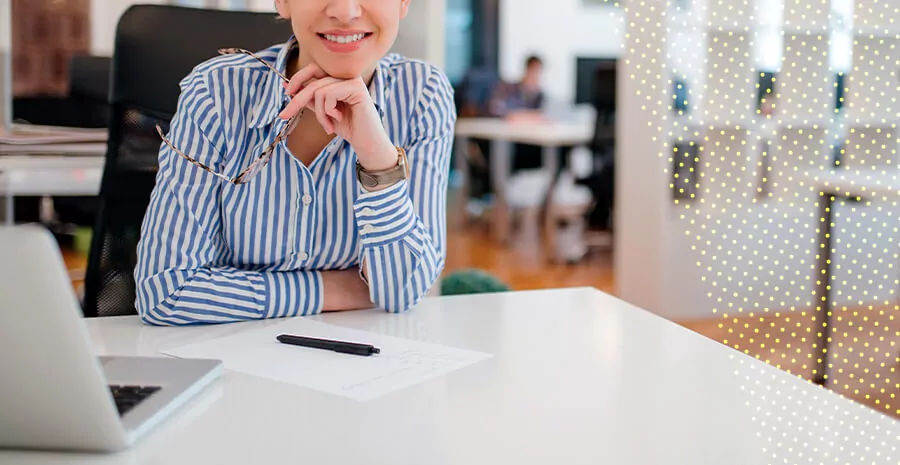 imagem de uma pessoa em uma mesa de trabalho sorrindo para a foto