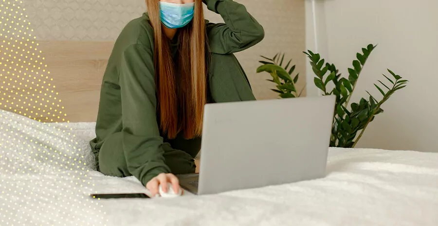 imagem de uma mulher de mascara olhando para o notebook