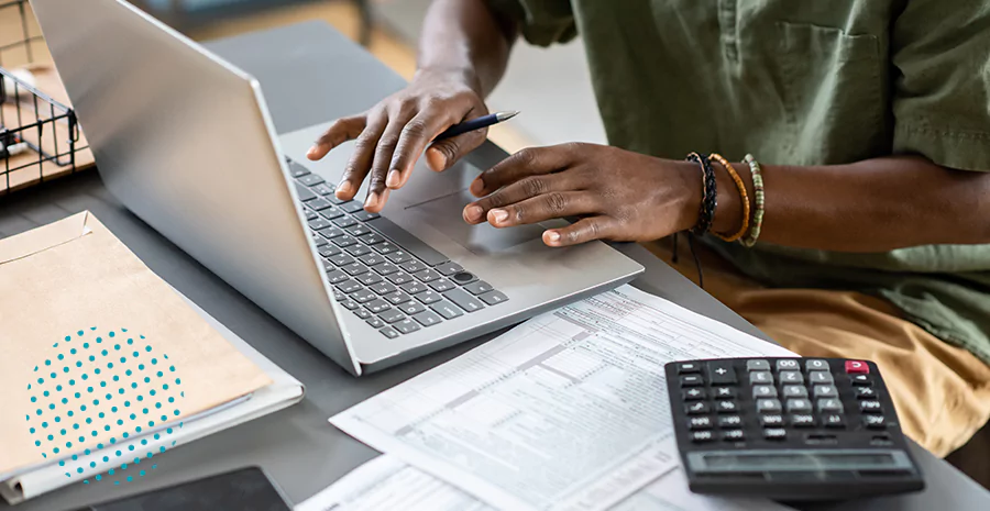 Mãos de pessoa usando notebook com calculadora e documentos de folha de pagamento online