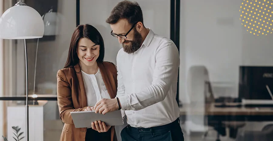 duas pessoas em pé conversando olhando para um papel