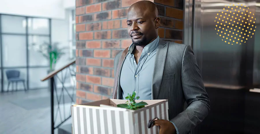 imagem de um homem segurando uma caixa com coisas de escritório representando uma demissão