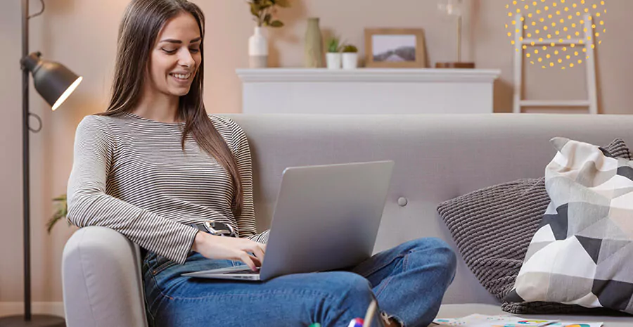 imagem de uma mulher sentada no sofá com um notebook no colo