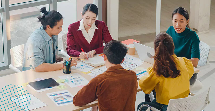 imagem de um grupo ao redor de uma mesa, todos olham para o centro