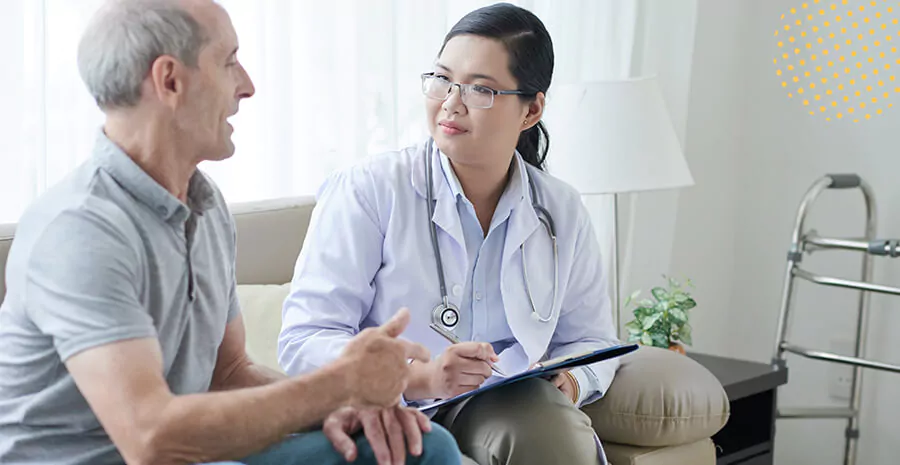 imagem de uma médica sentada conversando com o paciente ao lado, anotando em sua prancheta com papel e caneta