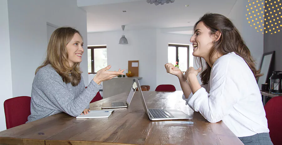 imagem de duas mulheres sentadas conversando uma de cada lado e uma mesa no meio com dois notebooks aplicando o teste de integridade