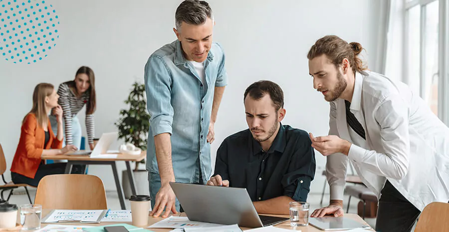 Imagem com foco em 3 homens em volta de um computador