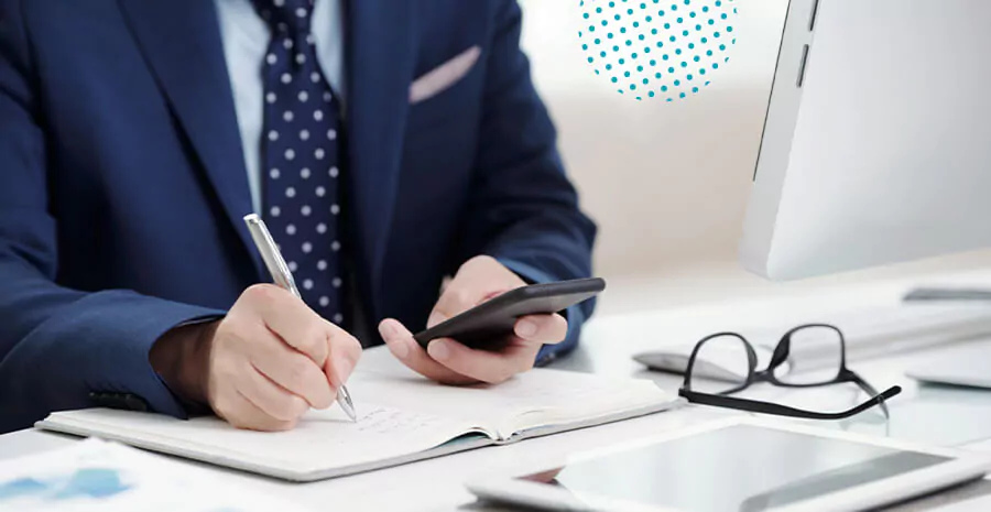 imagem de um homem de terno mexendo no celular e escrevendo em um caderno