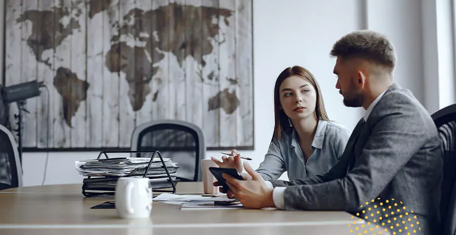 imagem de um homem e uma mulher sentados num ambiente de trabalho conversando
