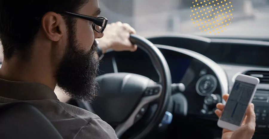 imagem de um homem dirigindo um carro e observando o caminho no celular