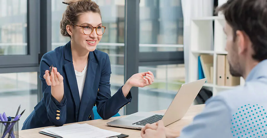 imagem de uma mulher sorrindo em um escritório na frente de um computador e de um homem