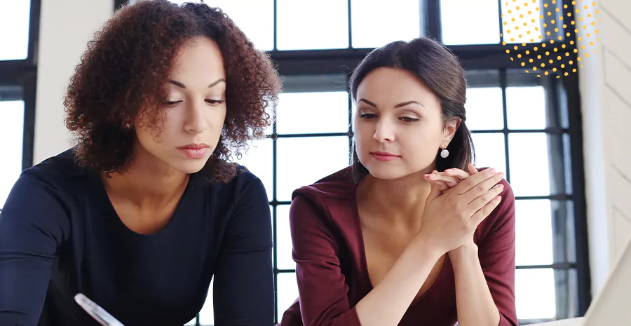 imagem de duas mulheres sentadas uma ao lado da outra olhando para baixo