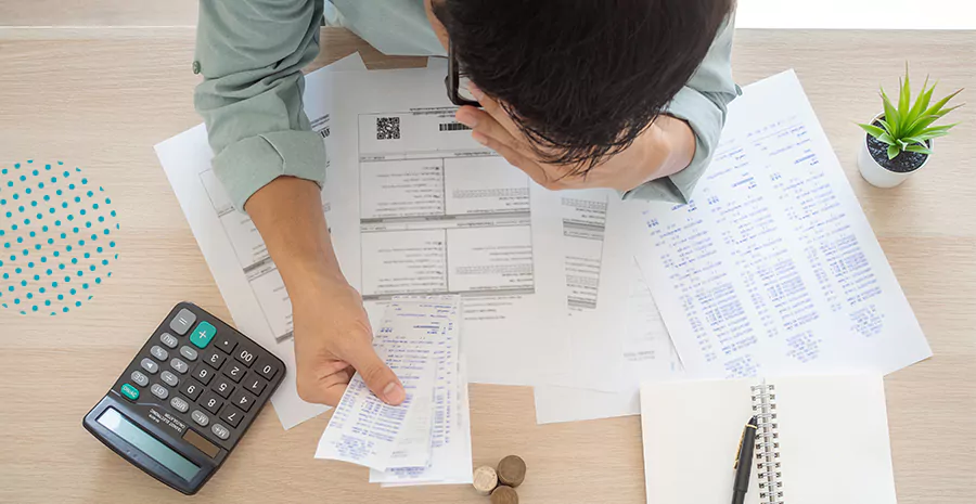 imagem de um homem segurando contas em papel com a mão na cabeça preocupado