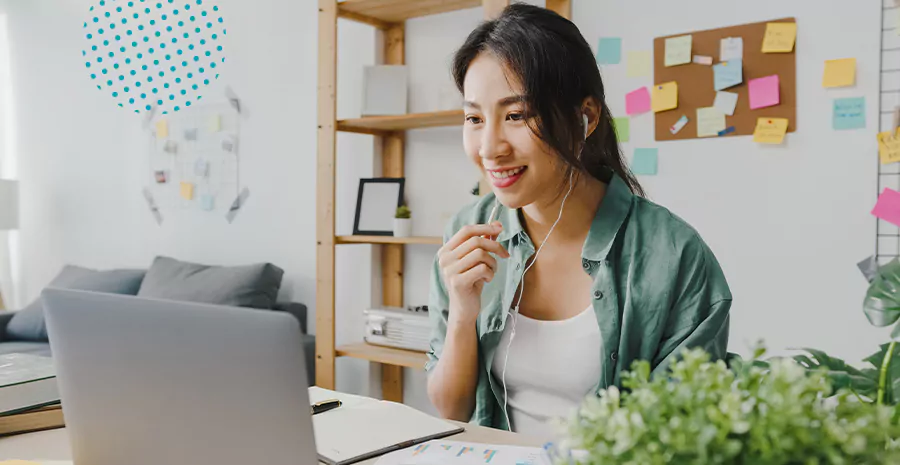 imagem de uma mulher sentada na frente do computador falando com outra pessoa usando fone de ouvido