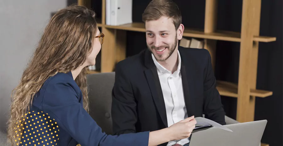 imagem de um homem e uma mulher sorrindo e conversando sentados em uma mesa