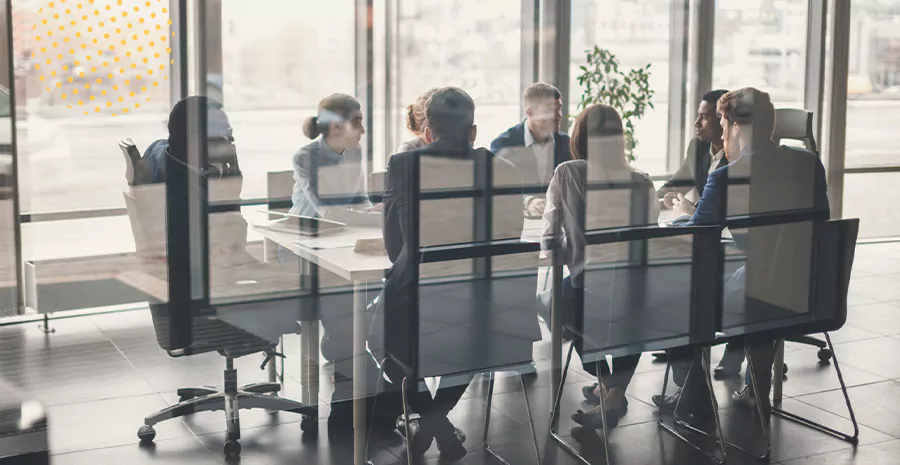 imagem de pessoas sentadas ao redor de uma mesa em uma sala de empresa