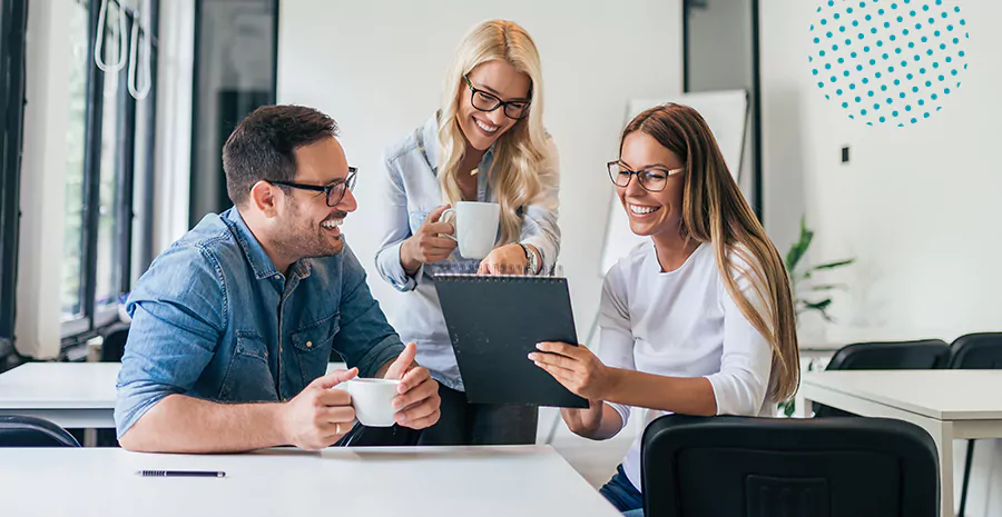 imagem de duas mulheres e um homem sentados sorrindo olhando para um tablet