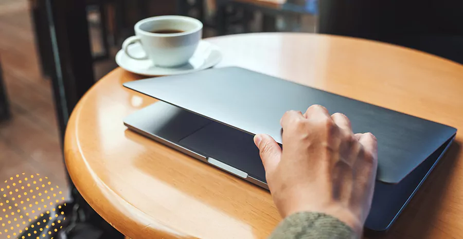 imagem de uma pessoa fechando o computador com uma xícara de café ao lado