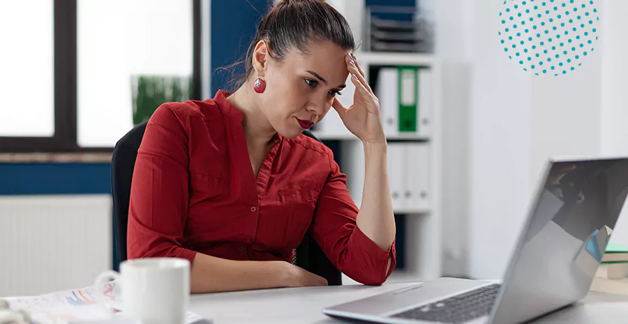 imagem de uma mulher sentada na frente do computador com feição séria