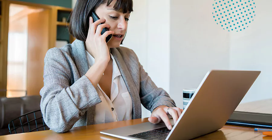 imagem de uma mulher sentada na frente de um computador falando ao telefone
