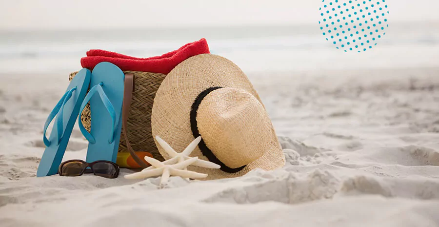 imagem de um chinelo bolsa de praia e chapéu em cima da areia da praia