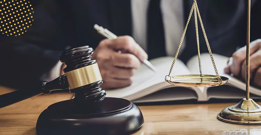 imagem de um homem sentado em uma mesa escrevendo com um martelo de juiz ao lado