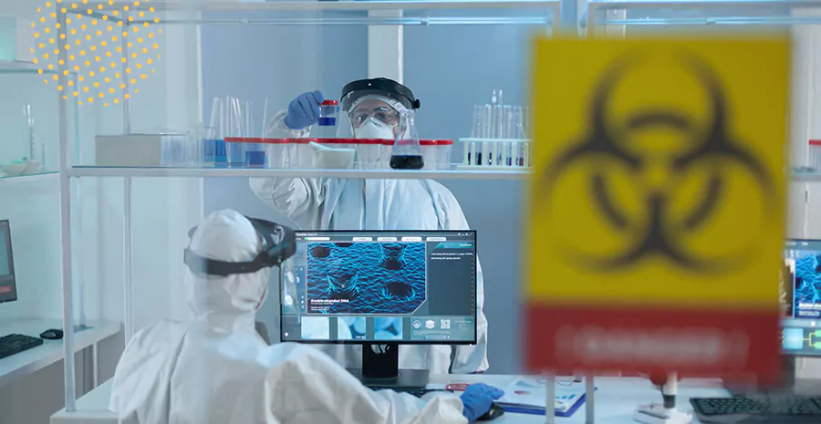 imagem de duas pessoas trabalhando em um laboratório usando equipamentos de proteção