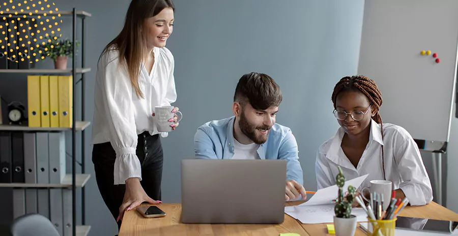 imagem de duas mulheres e um homem olhando para folhas de papel em uma mesa