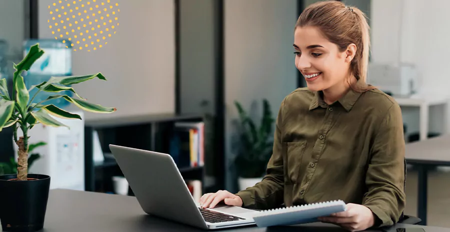 imagem de uma mulher sorrindo sentada na frente de um computador
