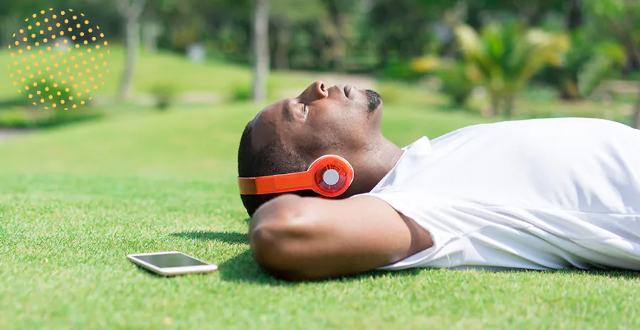 imagem de um homem deitado na grama ouvindo música