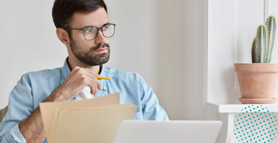 imagem de um homem sentado segurando folhas de papel e um lápis