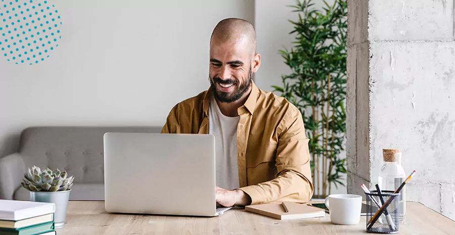 imagem de um homem sorrindo sentado na frente de um computador