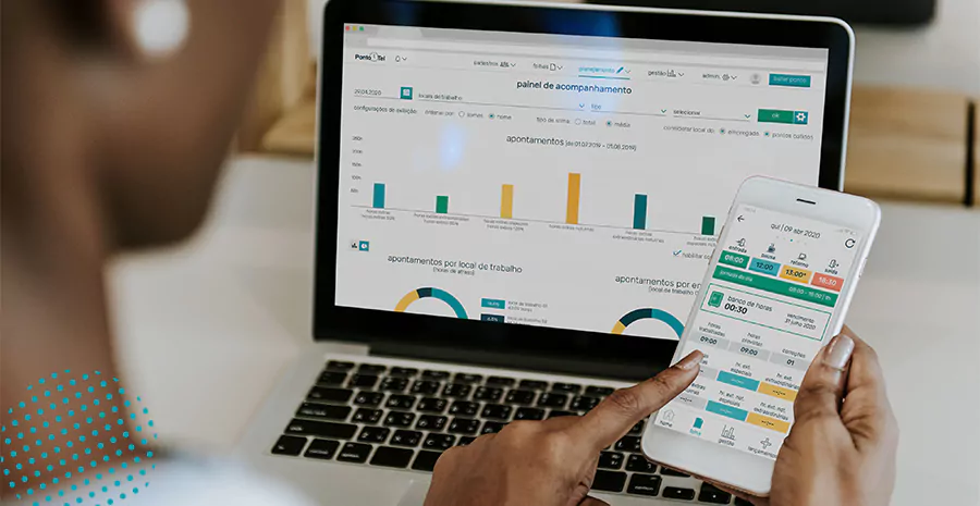 imagem de uma mulher sentada na frente de um computador e segurando um celular usando o aplicativo de controle de ponto da pontotel