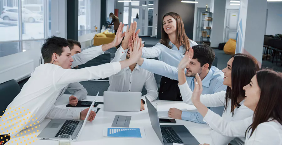 imagem de um grupo de pessoas sentado ao redor de uma mesa juntando as mãos no centro se cumprimentando