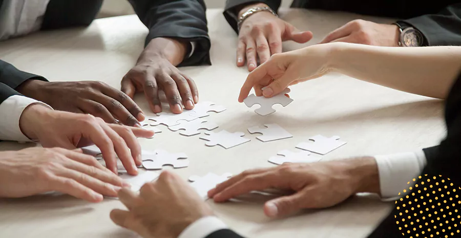 imagem de um grupo de pessoas sentado ao redor de uma mesa entendendo as mãos no centro em cima de um papel
