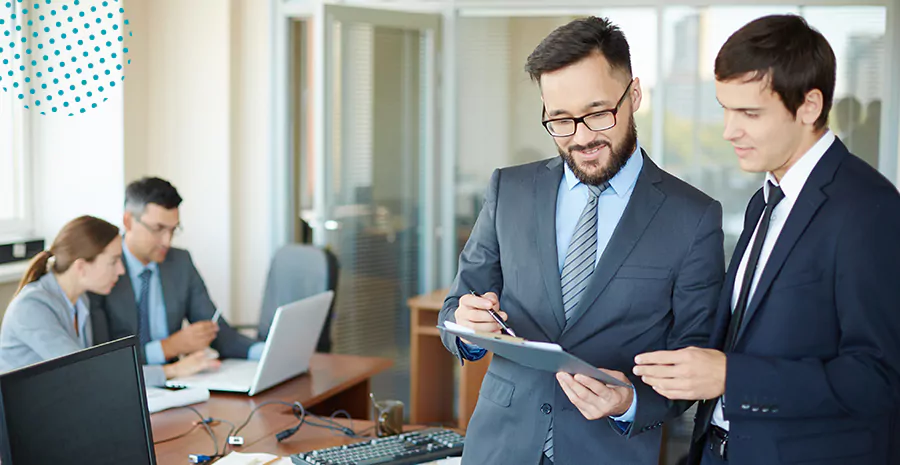 imagem de dois homens em pé em um escritório conversando segurando um tablet