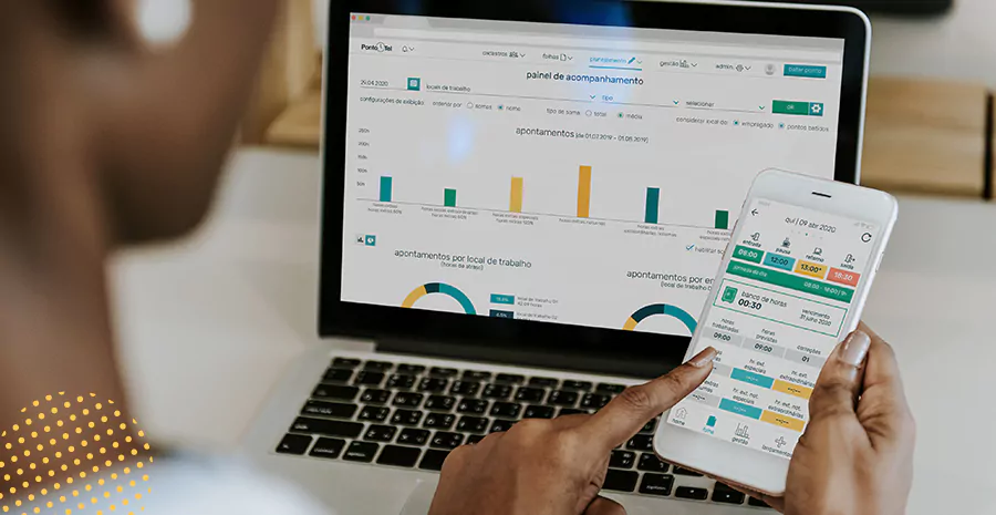 imagem de uma pessoa sentada na frente de um computador e segurando um celular usando o aplicativo de controle de ponto da pontotel