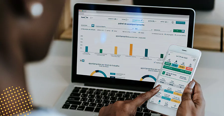 imagem de uma pessoa sentada na frente de um computador e segurando um celular usando o aplicativo de controle de ponto da pontotel
