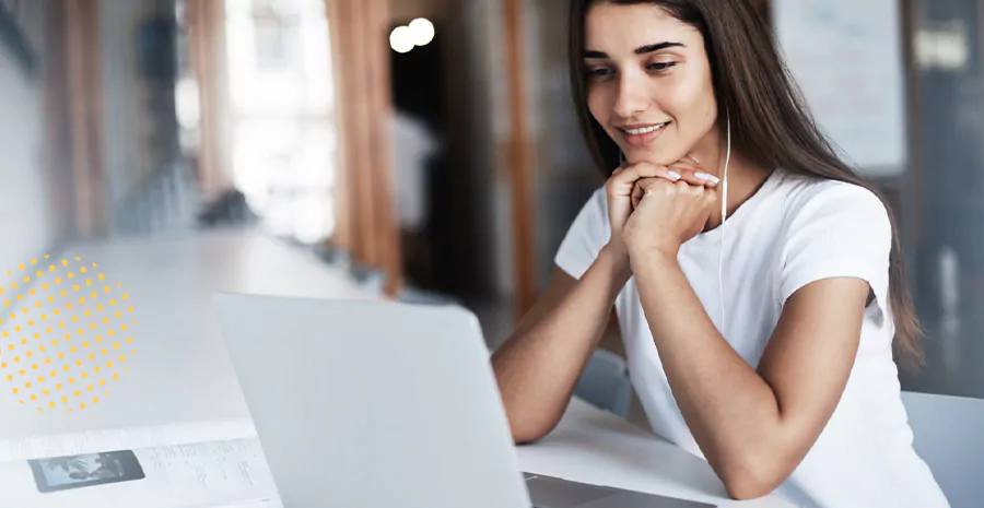 imagem de uma mulher sentada na frente de um computador sorrindo e usando fones de ouvido