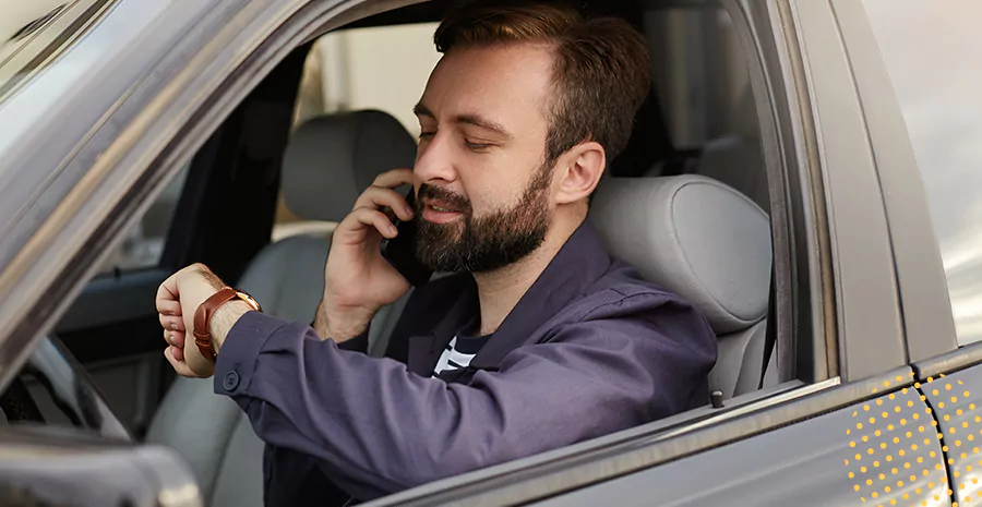 imagem de um homem dentro de um carro falando ao telefone e olhando para seu relógio de pulso