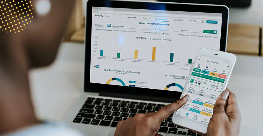 imagem de uma pessoa sentada na frente de um computador e segurando um celular usando o aplicativo de controle de ponto da pontotel