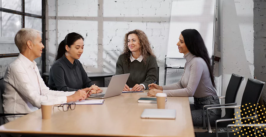 imagem de quatro pessoas sentadas ao redor de uma mesa em um escritório