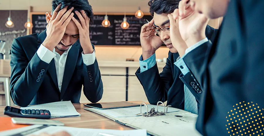 imagem de três homens sentados ao redor de uma mesa preocupados