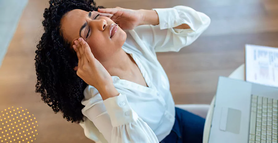 imagem de uma mulher sentada na frente de um computador preocupada com as mãos no rosto