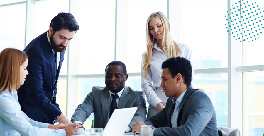 imagem de um grupo de pessoas ao redor de uma mesa conversando e olhando para um computador