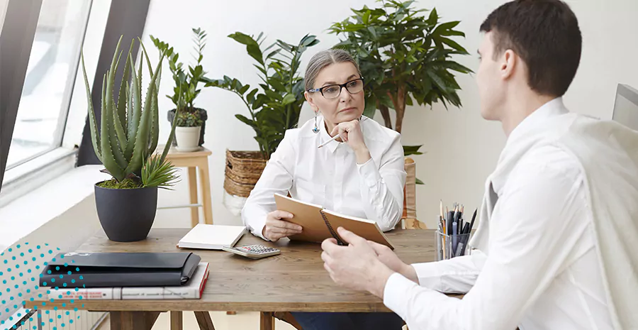 imagem de um homem e uma mulher sentados ao redor de uma mesa conversando