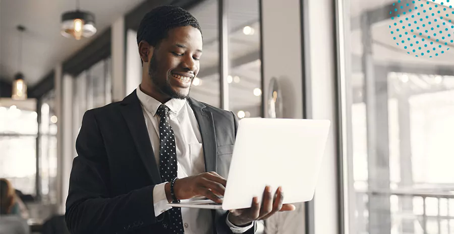 imagem de um homem em pé sorrindo segurando um computador