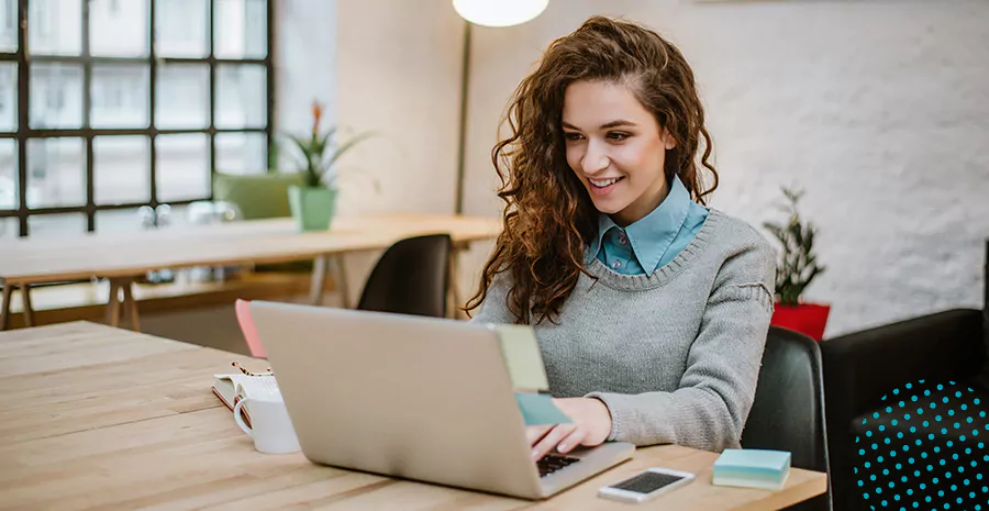 imagem de uma mulher sorrindo sentada na frente de um computador